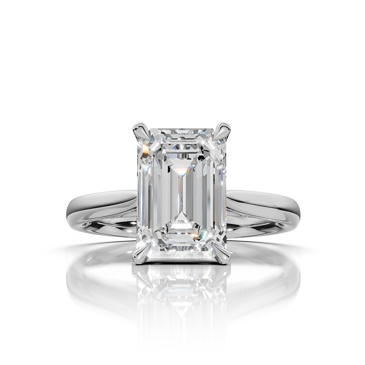 An emerald-cut diamond solitaire ring in a polished four-prong white gold or platinum setting, centered on a reflective white surface.