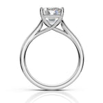 A silver solitaire engagement ring with a round brilliant-cut diamond, shown from a top-down perspective on a white background with a soft reflection below.