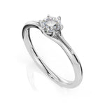 A classic solitaire engagement ring featuring a round brilliant-cut diamond set in a polished silver-colored metal band, shown on a clean white background with a soft reflection.