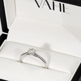 A low set round diamond solitaire with cathedral shoulders in 18ct white gold, displayed inside an open white VAHE ring box.