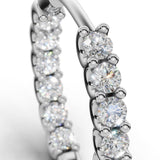 ILAYDA diamond huggie earrings in white gold, macro detail of the claw-set diamonds and U-scallops