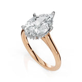 A rose gold ring with a large pear-cut diamond center stone and a halo of small diamonds, set on a clean white background.