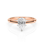 Rose gold ring with a pear-shaped diamond on a white background