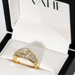 A gold ring with a diamond-encrusted geometric setting, displayed inside an open white jewelry box with the brand name VAHE visible on the inner lid.