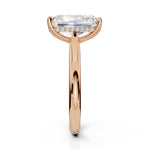 A rose gold engagement ring featuring a large rectangular emerald-cut clear center stone and a halo of small round-cut stones on the band, shown against a solid white background.