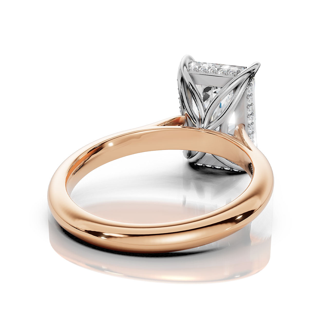 A close-up studio shot of a ring with a polished rose gold band and a silver-toned setting holding a rectangular gemstone, shown on a clean white background with a soft reflection.