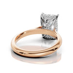 A close-up studio shot of a ring with a polished rose gold band and a silver-toned setting holding a rectangular gemstone, shown on a clean white background with a soft reflection.