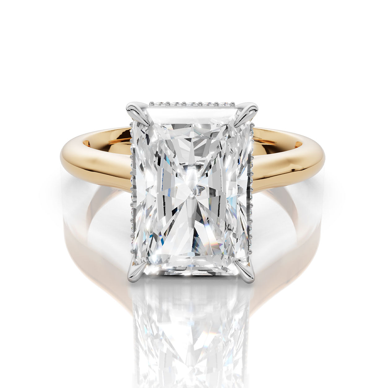 An emerald-cut diamond engagement ring with a yellow gold band and small diamond accents on the shoulders, set against a clean white background with a soft reflection.