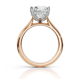 A rose gold diamond ring with a large round-cut center stone and smaller accent stones in a silver-colored setting, shown on a clean white background with a soft reflection below.