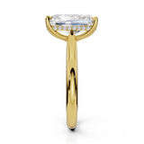 A yellow gold engagement ring featuring a large rectangular emerald-cut center stone and a halo of small round stones along the band, shown against a solid white background.