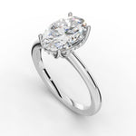 A silver engagement ring featuring a large oval-cut clear gemstone in a prong setting, accented by a halo of small round stones on a clean white background.