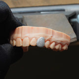  dentures with a diamond-studded grill held by a gloved hand